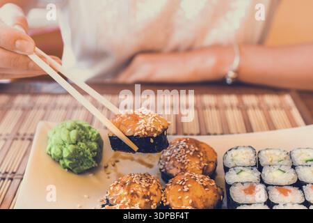 Frau mit asiatischen Stäbchen isst Sushi in Street Cafe Stockfoto