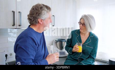 Seniorenpaar, die sich morgens im Kitchen-Pyjama unterhalten Stockfoto
