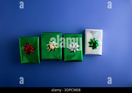 Kreative handgemachte Geschenkboxen aus weihnachtlichem Grün und silbernem Papier isoliert auf blauem Hintergrund, Draufsicht Stockfoto