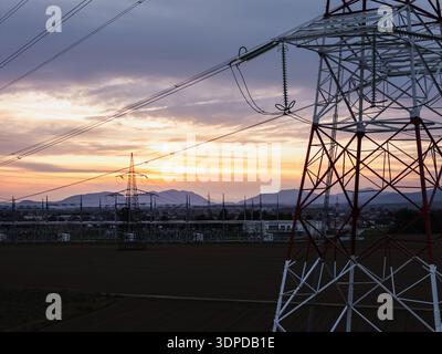 Luftaufnahme einer Hochspannungs-Unterstation mit Transformatoren und Leitungen in einem ländlichen Gebiet bei Sonnenuntergang. Stockfoto