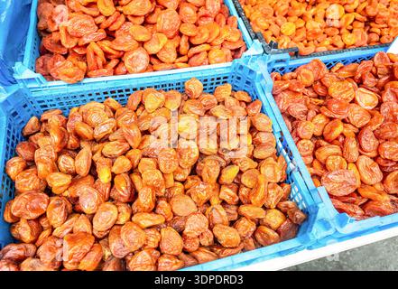 Ökologische usbekische getrocknete Aprikosen in Plastikkisten auf einem lokalen Bauernmarkt. Großer Haufen getrockneter Aprikosen, getrocknete Früchte, gesundes Dessert, vegetarisches Essen Stockfoto