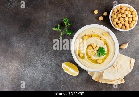 Traditioneller Hummus mit Olivenöl, Kichererbsen und Pitabrot auf dunklem Hintergrund. Draufsicht. Kopierbereich Stockfoto