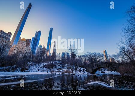 Atemberaubender Blick auf die Gapstow Bridge im Central Park in New York City an einem kalten Wintertag mit der beeindruckenden Billionaire's Row im Hintergrund Stockfoto