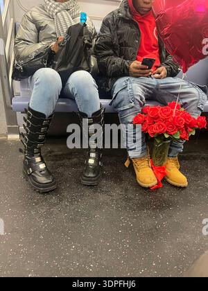 Romantisches Paar, das sich auf einer Bank in stilvollen Winterschuhen mit leuchtenden roten Blumen und warmer urbaner Atmosphäre mit weichem natürlichem Licht entspannt. Stockfoto