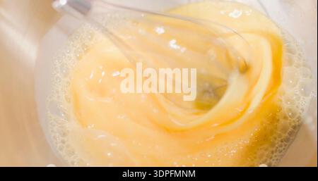 Mischung aus Eiern und Öl, die tagsüber in einer Schüssel für ein Rezept in der Küche geschlagen werden Stockfoto
