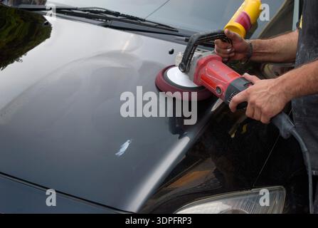autopolierwachs. Arbeiter Hände halten einen Polierer. Stockfoto