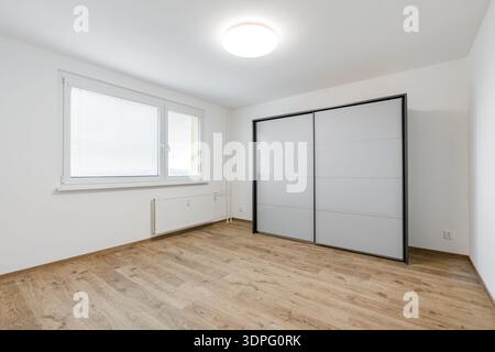Leeres, modernes Apartment-Schlafzimmer mit verschiebbarem Kleiderschrank und Fenster Stockfoto