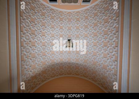 Valletta, Malta - 12. August 2025: Gewölbtes Kirchengewölbe in Valletta mit verzierten geometrischen Reliefs aus Stuck und zentralem Wappenschild, beleuchtet durch sanfte Inte Stockfoto