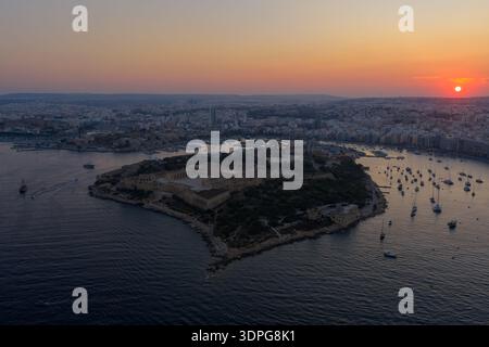 Luftaufnahme von Manoel Island im Hafen von Marsamxett bei Sonnenuntergang in der Nähe von Gzira, Malta, mit befestigter Küste und verankerten Yachten. Stockfoto