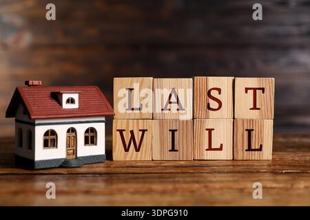 Letzter Wille. Worte aus Würfeln mit Buchstaben und Hausmodell auf Holztisch Stockfoto