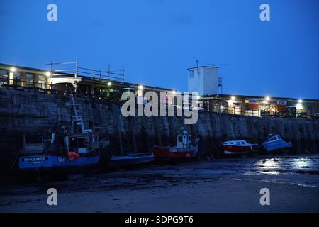 Margate Harbour in der blauen Abenddämmerung mit farbenfrohen Fischerbooten bei Ebbe, beleuchteten Hafenmauern, feuchten Sandspiegeln, Kent England Küste Stockfoto
