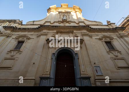 Flacher Blick auf die orthodoxe Nikolaikirche in Valletta mit der barocken Kalksteinfassade, dem bogenförmigen Eingangsportal und den dekorativen Nischen u Stockfoto