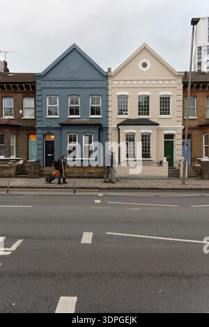 Die Leute laufen an viktorianischen Häusern auf der Queenstown Road in Battersea London vorbei. Stockfoto
