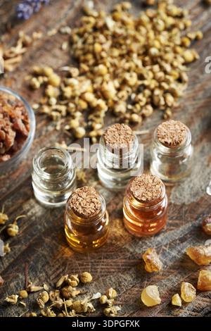 Auswahl ätherischer Öle in Glasflaschen mit Weihrauch, Myrrhenharz und getrockneten Kräutern Stockfoto