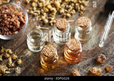 Mischung ätherischer Öle in Glasflaschen mit Weihrauch, Myrrhe und getrockneten Kräutern Stockfoto