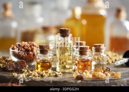 Auswahl ätherischer Öle in Glasflaschen mit Weihrauch, Myrrhe und getrockneten Kräutern und Blüten Stockfoto