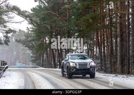 Geländewagen auf der Kurve einer verschneiten Waldstraße. Bewegungssteuerung. Stockfoto