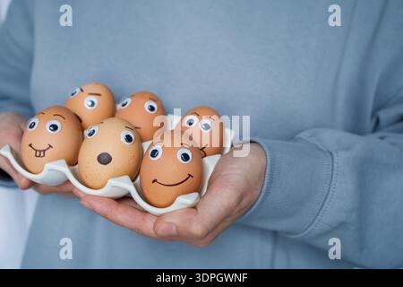 Sechs lustige, handgemachte Osteremoji-Eier auf einem Stand in Frauenhänden. Christliche Ostertradition, kreative, handgemachte Urlaubsideen für Kinder Stockfoto