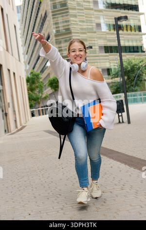 Glückliche junge Studentin, die auf dem Campus begrüßt Stockfoto