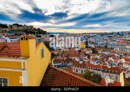 Terrakotta-Dächer säumen den Sonnenuntergang am Miradouro da Graca in Lissabon, Portugal, mit Blick auf das Schloss St. George auf dem Hügel, das Kloster Carmo und die 25 Stockfoto