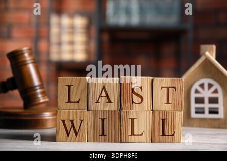 Die Worte sind aus Holzwürfeln mit Buchstaben, Hausmodell und Hammer auf dem Tisch. Bannerdesign Stockfoto