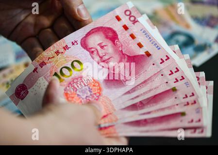 China. Februar 2026. In dieser Fotoabbildung fächert eine Hand einen Stapel 100-Yuan-RMB-Banknoten aus und enthüllt ihre Seriennummern und das Porträt von Mao Zedong vor einem verschwommenen Hintergrund anderer Währungen. Der chinesische Yuan hat in den letzten Perioden leichte Schwankungen gegenüber dem US-Dollar erlebt, wobei der allgemeine Trend einer moderaten Aufwertung zu verzeichnen war. Quelle: SOPA Images Limited/Alamy Live News Stockfoto