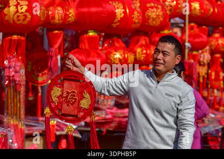 Fuyang, China. Februar 2026. Ein Mann hält glücklich eine rote Laterne mit „Fu“-Charakter in der Hand, während er auf dem Neujahrsmarkt in Fuyang shoppt. Als wichtigstes traditionelles chinesisches Mondneujahr fällt das Frühlingsfest am 17. Februar dieses Jahres. Eine wichtige Tradition besteht darin, Frühlingsfest-Couplets und rote Laternen aufzuhängen, sowie andere festliche rote Dekorationen. Mit dem nahenden Festival wird die festliche Atmosphäre in den Städten immer lebendiger. Quelle: SOPA Images Limited/Alamy Live News Stockfoto