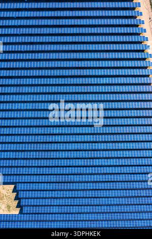 Reihen blauer Solarpaneele erzeugen ein auffälliges geometrisches Muster, wie es von einer Drohne über einem Solarpark in der kalifornischen Mojave-Wüste aus gesehen wird. Die parallele... Stockfoto