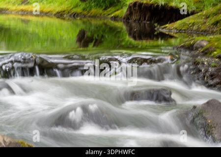 Ein Wasserstrom fließt durch ein felsiges Gebiet. Die Szene ist friedlich und ruhig. Stockfoto
