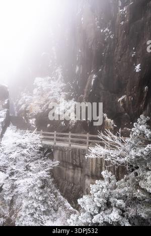 Huangshan, China: Wanderweg an der Klippe in der gefrorenen Landschaft des Gelben Berges in Mount Huangshan in China im Winter Stockfoto