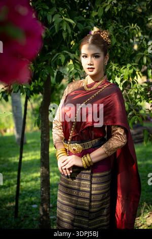 Eine elegante Thai-Frau in schöner traditioneller Tracht posiert im üppigen Terracotta-Garten in Lamphun, Thailand. Stockfoto
