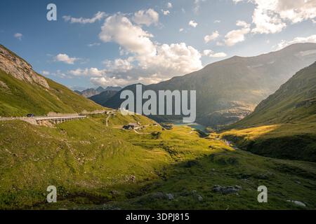 Malerische Bergtalstraße, die zum Pasterze-Gletscher führt, mit gewundenen Kurven, abgelegenen Berghütten und einem türkisfarbenen Gletschersee Stockfoto