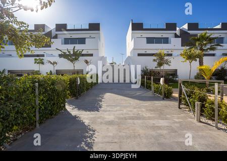 Heller, sonniger Blick auf moderne Wohngebäude mit gepflegtem Weg, zentraler Treppe und minimalistischen weißen Fassaden in modernen Wohngebäuden Stockfoto