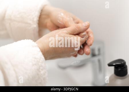 Nahaufnahme einer Frau, die Creme auf die im Bad stehenden Hände aufträgt. Kopierbereich Stockfoto