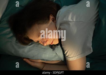 Frau mit Schlaflosigkeit, die mit offenen Augen im Bett liegt. Schlafstörungen, Probleme in der Nacht. Kopierbereich. Draufsicht Stockfoto