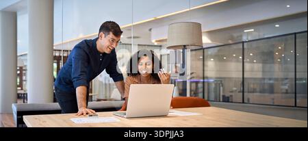 Zwei junge, vielbeschäftigte Kollegen, Geschäftsleute, die in modernen Büros ein Notebook verwenden. Stockfoto