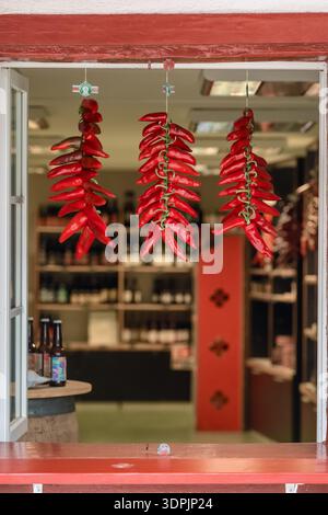 Nahaufnahme der roten Espelette-Chili-Paprika, die in Strings hängen Stockfoto