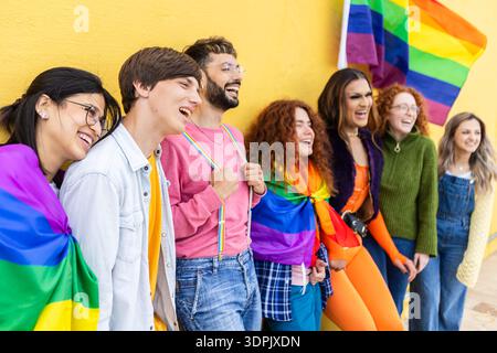 Verschiedene LGBT-Freunde stehen mit Regenbogenfahne Stockfoto