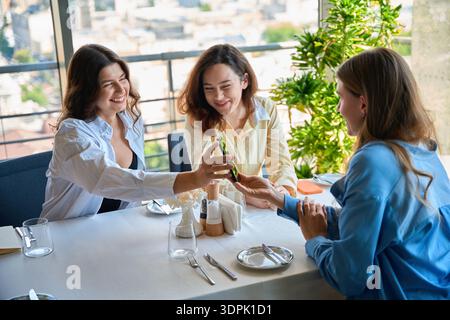 Glückliche Freundinnen sitzen im Restaurant mit dem Handy Stockfoto