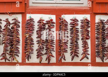 Rote Espelette-Paprika trocknen an der traditionellen baskischen Hausfassade Stockfoto