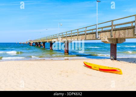 Rot-gelbes Kajak am Sandstrand in der Nähe des Piers im Sommerresort Goehren, Insel Rügen, Ostsee, Deutschland Stockfoto