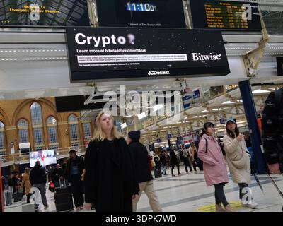 Liverpool Street Station, LONDON, Großbritannien. Februar 2026. Pendler laufen an einem Londoner Hauptbahnhof vorbei an einer digitalen Werbeschilderung von JCDecaux. Auf dem Bildschirm wird eine Werbung für Bitwise Asset Management angezeigt, einen globalen Asset Manager für Kryptowährungen, der seine Lösungen für digitale Anlagen hervorhebt. Stockfoto