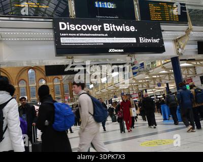 Liverpool Street Station, LONDON, Großbritannien. Februar 2026. Pendler laufen an einem Londoner Hauptbahnhof vorbei an einer digitalen Werbeschilderung von JCDecaux. Auf dem Bildschirm wird eine Werbung für Bitwise Asset Management angezeigt, einen globalen Asset Manager für Kryptowährungen, der seine Lösungen für digitale Anlagen hervorhebt. Stockfoto