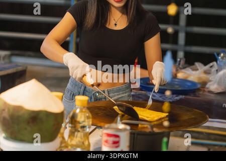 Zubereitung von Pfannkuchen süßen Roti an einem Straßenstand in Bangkok, mit einem traditionellen thailändischen Snack, der von einem lokalen Händler am Abend zubereitet wird Stockfoto