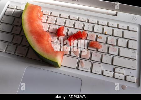 Nahaufnahme einer Wassermelone, die auf einer Computertastatur verschüttet wurde, 2026, USA Stockfoto