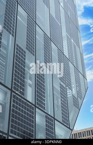 Modernes Glasgebäude mit integrierten Sonnenkollektoren zur Erzeugung nachhaltiger sauberer Energie. Stockfoto
