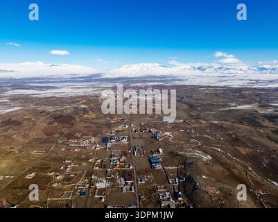 Eine Stadt mit vielen Häusern und einem Berg im Hintergrund. Der Himmel ist blau und die Sonne scheint Stockfoto