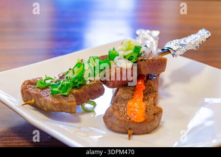 Köstlich gegrillte Rinderspieße mit frischen grünen Zwiebeln und scharfer Sauce Stockfoto