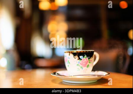 Gemütliche Café-Szene mit einer zarten Teetasse mit Blumenmuster Stockfoto