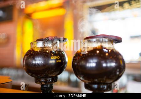 Satter Kaffee, der in eine Glasschale mit aufsteigendem Dampf gegossen wird Stockfoto